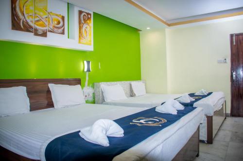 two beds in a room with green walls at Hotel Platinum in Kolkata