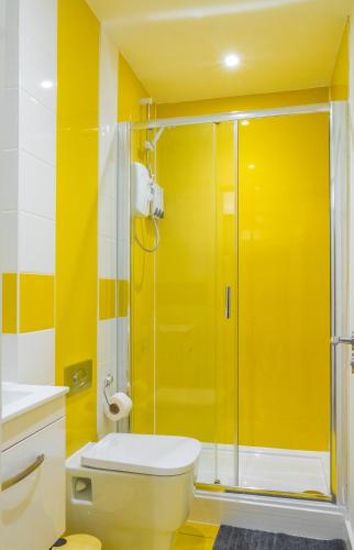 a yellow bathroom with a toilet and a shower at Exquisite Central Suites Sheffield in Sheffield