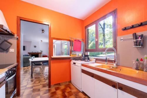 an orange kitchen with a sink and a table at Maison au bord de l'eau, Bain nordique in Guipry-Messac