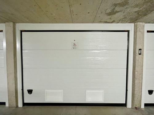 a white garage door with a sign on it at Il Ruscello Mountain Apartment in Madesimo