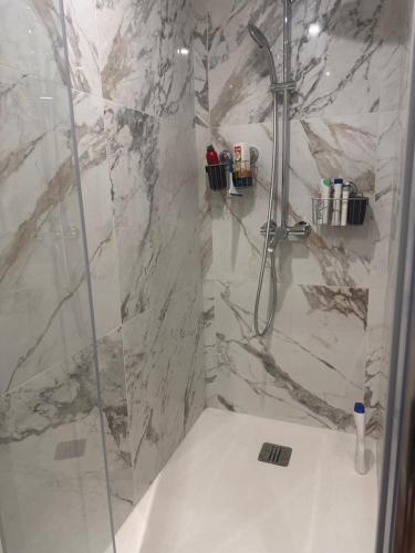 a bathroom with a shower and a white marble wall at Cosy Appartement Levallois-Perret in Levallois-Perret