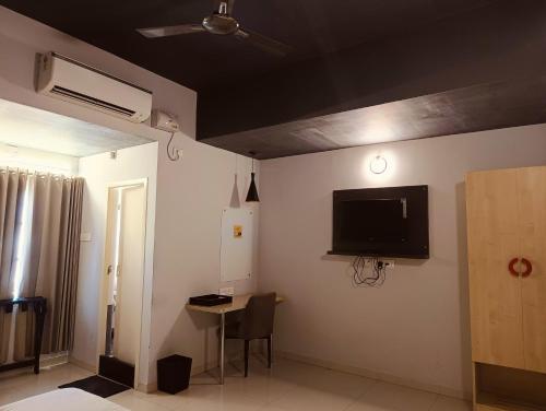 Habitación con TV en la pared y mesa. en Skyry Residency Tidel Park, en Coimbatore