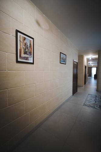 a hallway with a brick wall with two pictures on it at The Willows - Gozo in Għajnsielem
