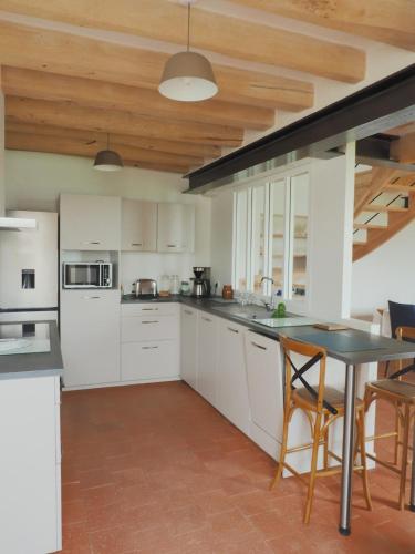 une cuisine avec des placards blancs et une table noire dans l'établissement Peace and quiet, à Coutures