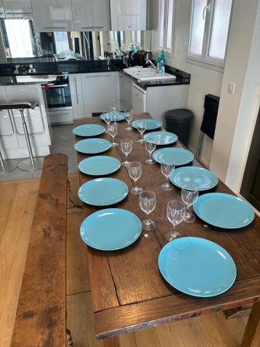 une longue table en bois avec des assiettes bleues et des verres à vin dans l'établissement LaBoucherieTrouville Maison 200m2 5 Chambres HyperCentre Trouville 13 pers plus bébés,, à Trouville-sur-Mer
