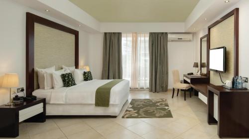达累斯萨拉姆Peninsula Hotel Dar Es Salaam的一间卧室配有一张床、一张书桌和一台电视
