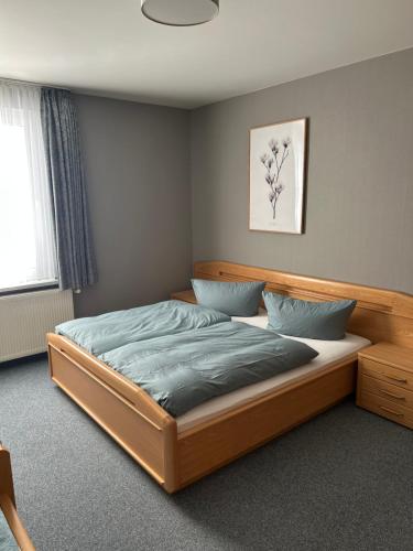a bedroom with a large wooden bed with blue pillows at Pension und Café "Alte Straßenmeisterei" in Hasselfelde