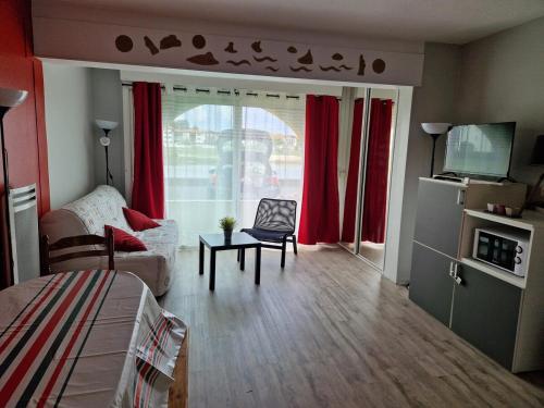 Cette chambre comprend un salon avec des rideaux rouges. dans l'établissement Appartement Socoa proche St Jean de luz Biarritz Espagne, à Socoa
