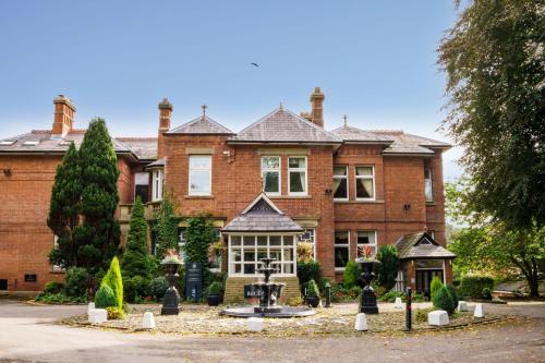 a large brick house with a fountain in front of it at Macdonald Kilhey Court Hotel in Wigan