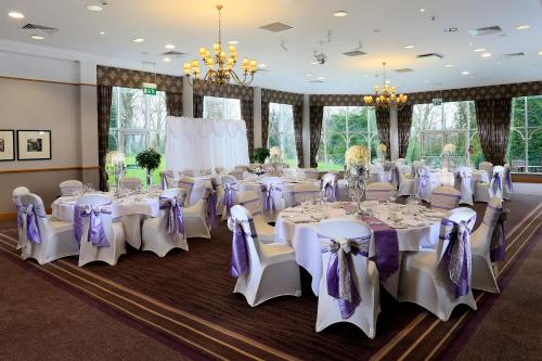 a room filled with tables and chairs with purple bows at Macdonald Kilhey Court Hotel in Wigan