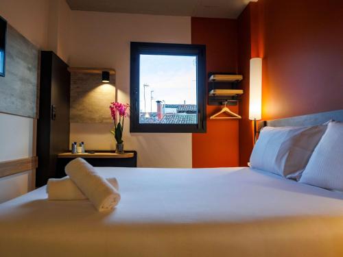 a bedroom with a white bed with a window at ibis budget Logroño Centro in Logroño
