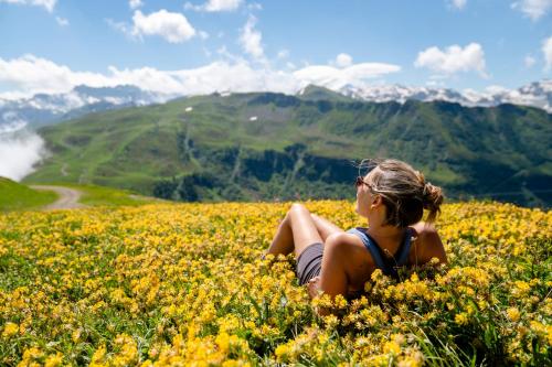 a woman sitting in a field of yellow flowers at Résidence Club MMV Samoens in Samoëns