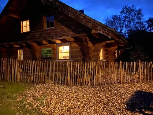 une cabane en rondins avec une clôture devant elle dans l'établissement Eifelurlaub - kanadisches Blockstamm Ferienhaus für 12 Personen, à Schleiden