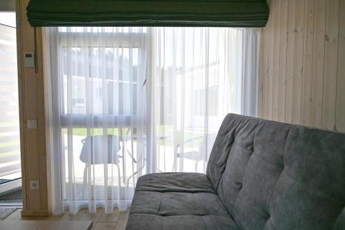 a living room with a couch and a large window at Kintų Perlas Vila dviems V in Kintai