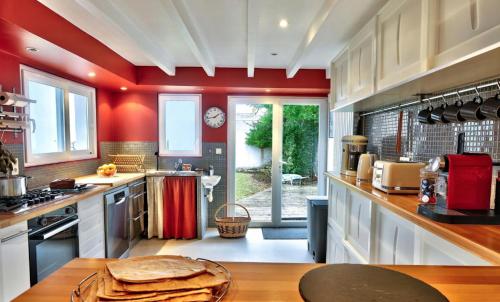une grande cuisine avec des murs rouges et un comptoir dans l'établissement Magnifique maison pour 9 - Saint Guénolé, à Penmarcʼh