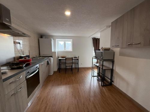 Il comprend une cuisine avec du parquet, des armoires et une table. dans l'établissement La Bohème-proche Stellantis-Technoland, à Vieux-Charmont