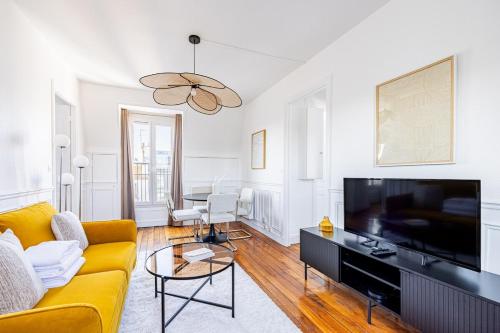 Il comprend un salon doté d'un canapé jaune et d'une télévision à écran plat. dans l'établissement Apartment 1 Bedroom # Paris 14 # Alesia, à Paris