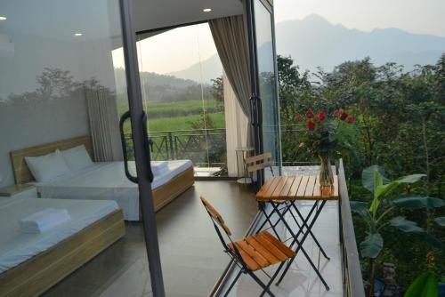 a bedroom with a balcony with a bed and a table at Timi Little Garden in Ba Vì