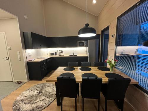a kitchen with a wooden table and black chairs at Rukan Helmi in Kuusamo