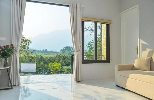 a living room with a couch and a large window at Timi Little Garden in Ba Vì