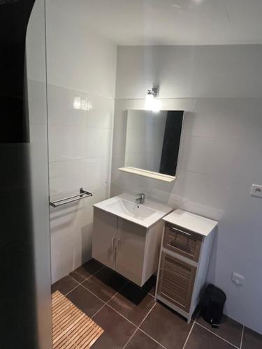 une salle de bain blanche avec un lavabo et un miroir dans l'établissement Maison individuelle type F2, à Alata