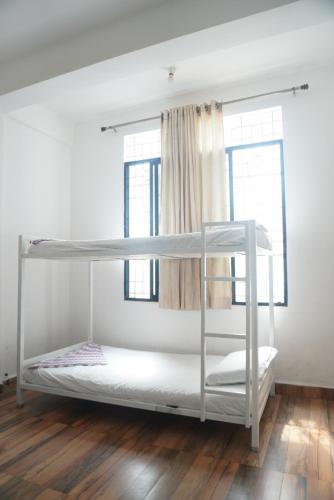 a bunk bed in a room with two windows at This is it Beachfront - Rooms, Cafe & Events in Arambol