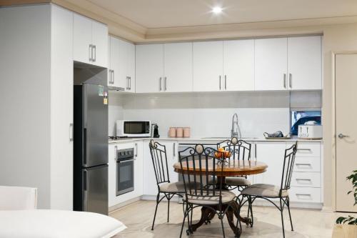a kitchen with white cabinets and a table and chairs at Terra de Sol A Mediterranean Escape in Perth in Perth