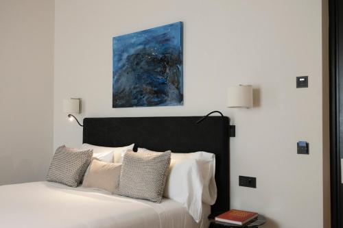 a bed with white pillows and a painting above it at Hotel Boutique Sidonia in Jerez de la Frontera
