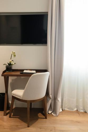 a white chair sitting next to a desk with a television at Hotel Boutique Sidonia in Jerez de la Frontera