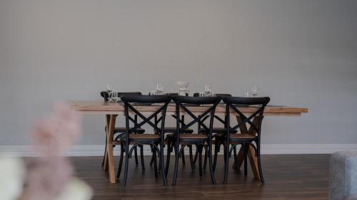 a dining room table with black chairs and a white wall at 35 Hamptons Luxury Escape Family Home Sleeps9 in Baldivis