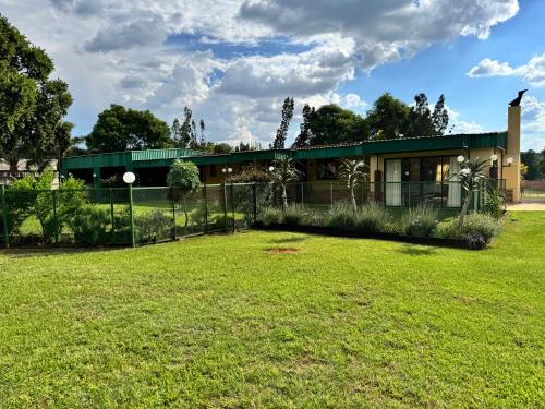 a house with a fence in front of a yard at EastClaire Guesthouse in Krugersdorp