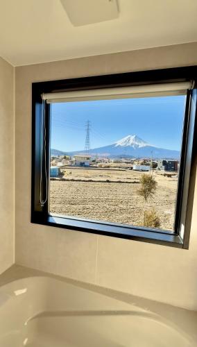 a bathroom window with a tub and a view of a mountain at 富士の宿燦々 in Fujiyoshida