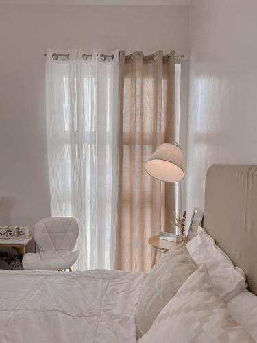 a bedroom with a bed and a chair and a lamp at Mesatierra Garden Residences in Davao City