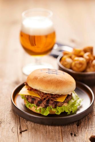 a hamburger on a plate with a glass of beer at Midgard Base Camp in Hvolsvöllur