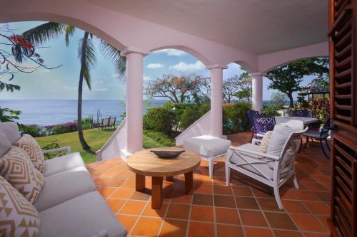 a porch with a table and chairs and the ocean at Cap Maison Resort & Spa in Cap Estate