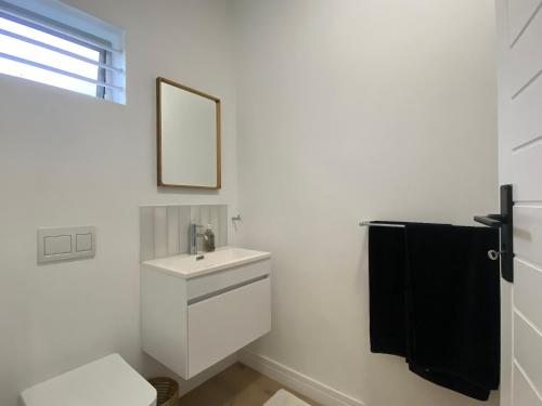 a white bathroom with a sink and a mirror at Bloom Homestead Apartment, Summerveld in Hillcrest