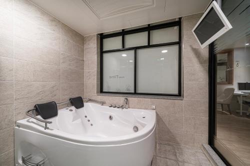 a bath tub in a bathroom with a window at Time Hotel in Yangsan