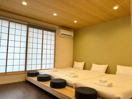 two beds with stools in a room with windows at ASOBO OSAKA Kuromon 1st in Osaka