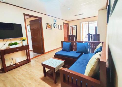 a living room with a blue couch and a flat screen tv at Zenmnist Properties - Two Bedroom dlx in Baguio