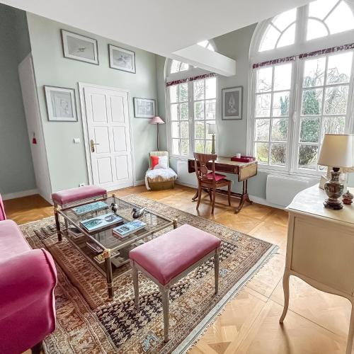 - un salon avec une table en verre et des chaises roses dans l'établissement L'orangerie White Palacio, à Versailles