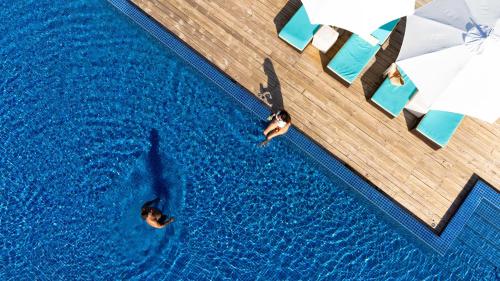 an overhead view of two people swimming in a swimming pool at Atmosphere Kanifushi - Premium All Inclusive with Free Transfers in Lhaviyani Atoll