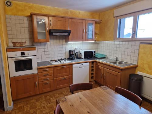 une petite cuisine avec des placards en bois et une table dans l'établissement Au Platelet, aux Rousses