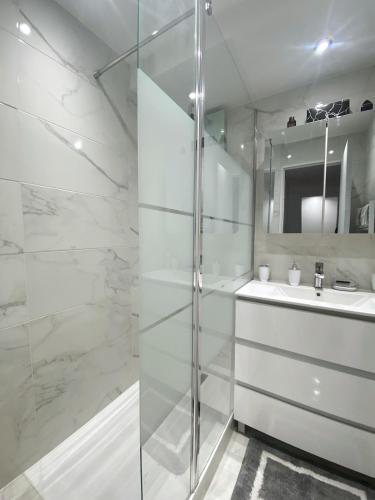 une salle de bain blanche avec une douche et un lavabo dans l'établissement Suite Prestige Paris-La Défense Balcon-Terrasse, à Courbevoie