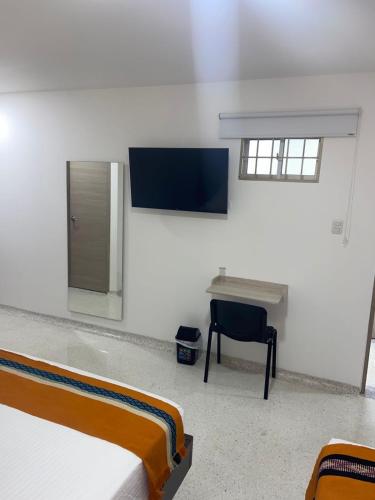 a white room with two beds and a desk at Hotel Tepia in Maicao