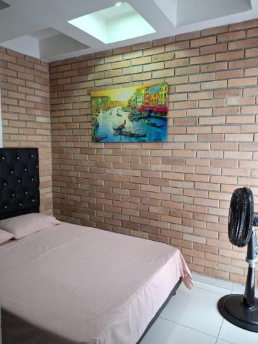 a bedroom with a brick wall with a bed and a painting at Hotel Santo llanero in Palmira