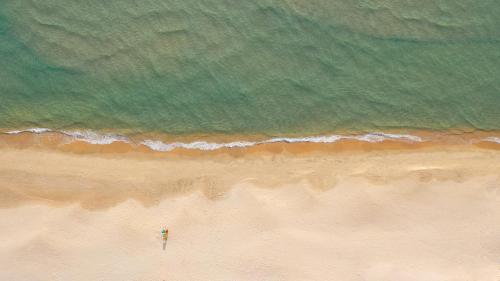 an overhead view of a beach with a person standing on the sand at The Ocean Resort by Fusion Quy Nhon in Quy Nhon