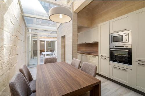 a kitchen with a wooden table and chairs at Melita Breeze House in Sliema