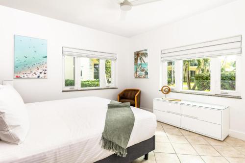 a white bedroom with a bed and two windows at 2 Bdrm Garden Marina View at The Yacht Club C4 in Providenciales