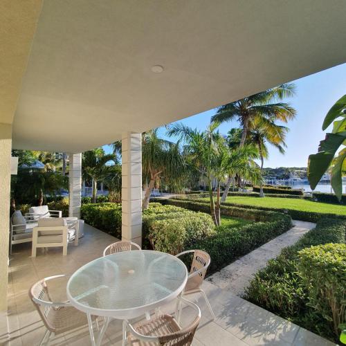 an outdoor patio with a glass table and chairs at 2 Bdrm Garden Marina View at The Yacht Club C4 in Providenciales