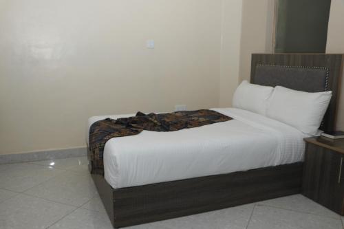 a bedroom with a bed with white sheets and pillows at Motel Clavina in Gilgil